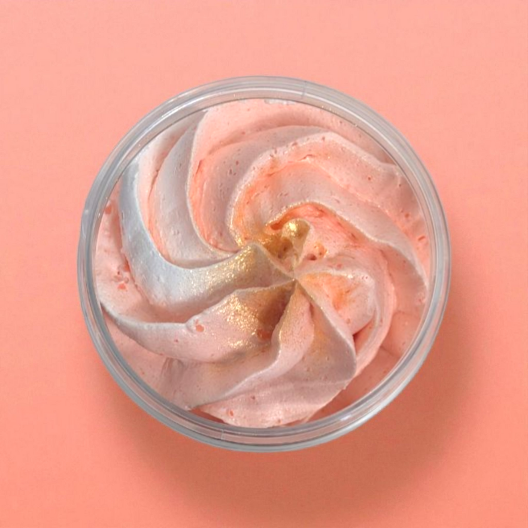 Peach and white whipped soap in a clear container on a coral pink background