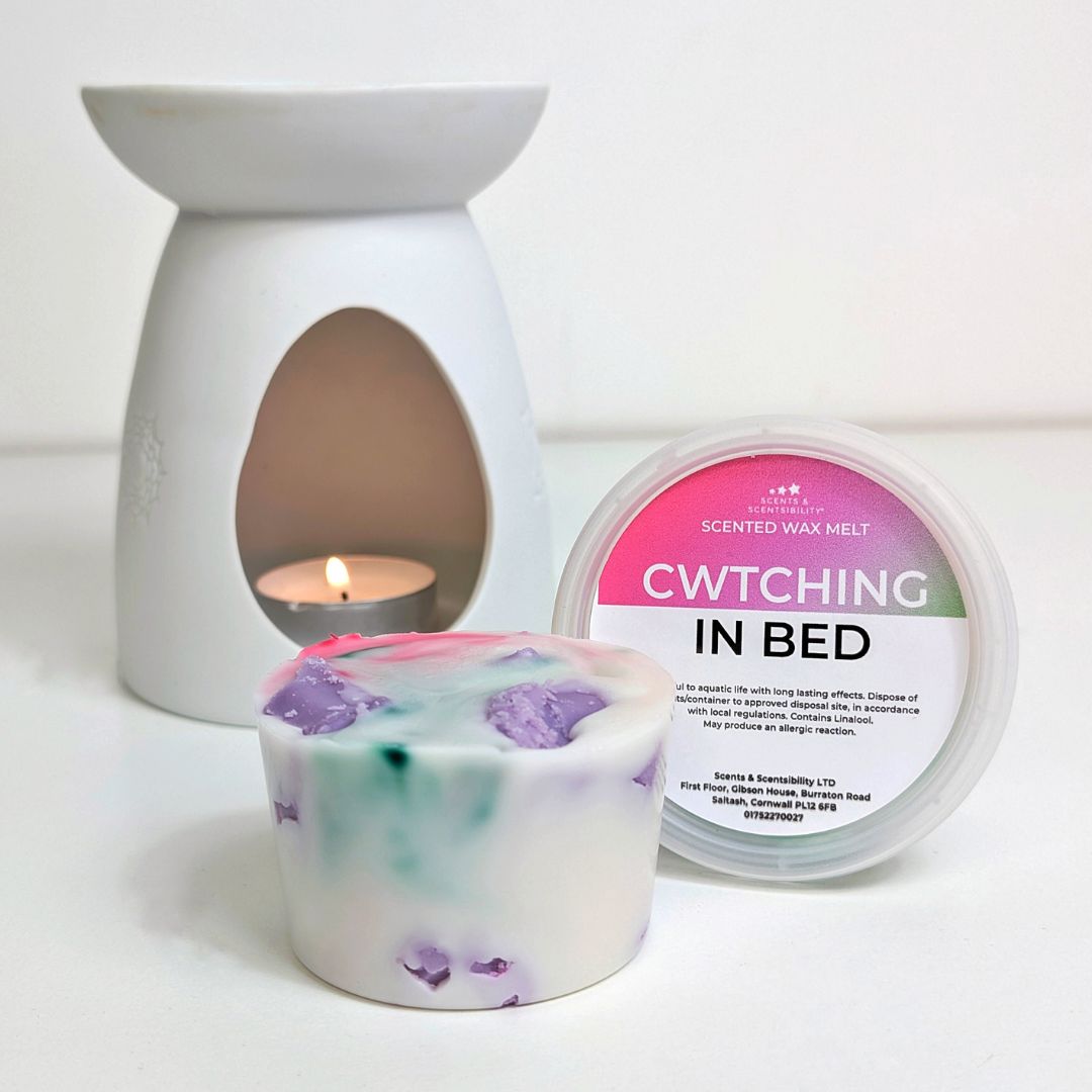 Scented wax melt container with a lit wax melt burner and packaging on a white background