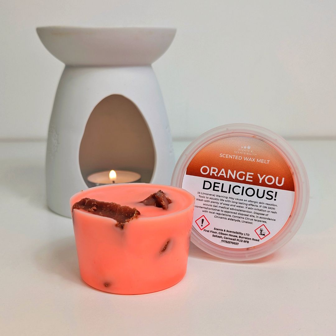 Neon orange scented wax melt with a white wax melt burner and container on a light background