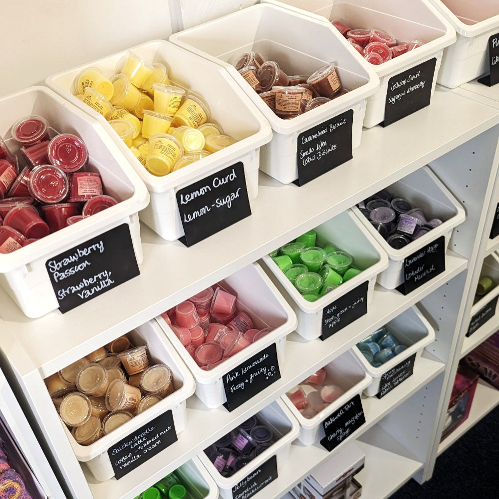 Shelf with labeled containers of various coloured wax melts