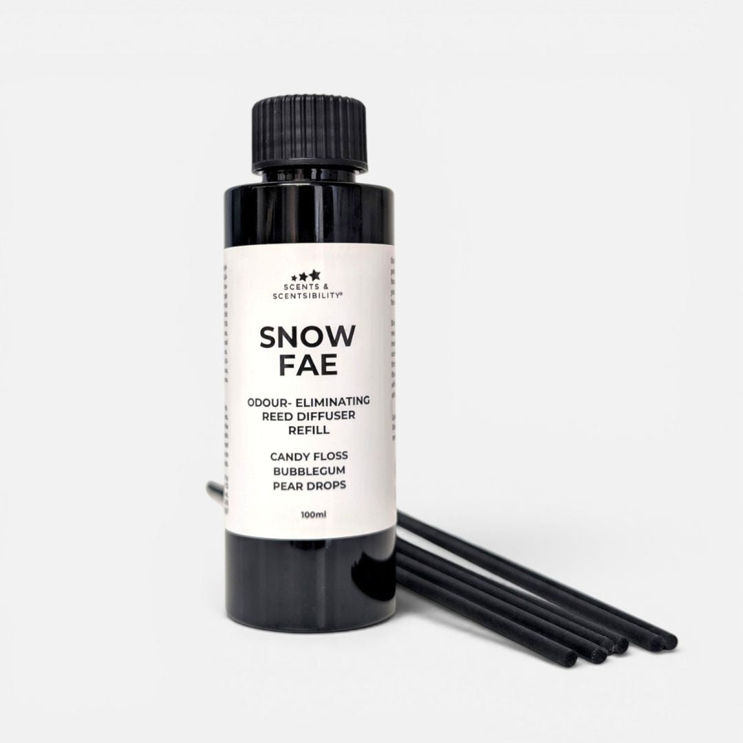 A black bottle of 'Snow Fae' odour-eliminating reed diffuser refill with a white label, shown next to six black reeds on a light gray background.