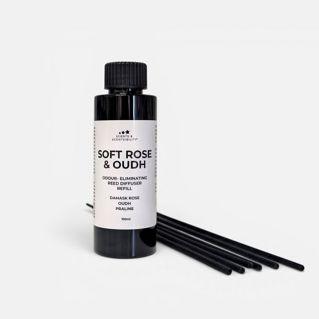 A black bottle of 'Soft Rose & Oudh' scent-eliminating Reed Diffuser Refill by Scents & Scentsibility, shown with six black reeds on a clean white background.