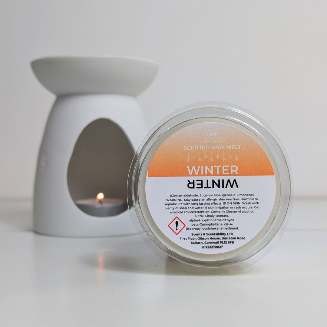 Scented wax melt container labeled 'Winter' with a lit candle in the background.