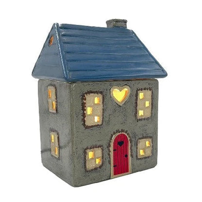 Decorative house-shaped wax melt warmer with a blue roof and red door on a white background