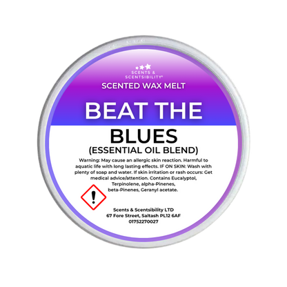 A round tub of Scents & Scentsibility 'Beat the Blues' scented wax melt, featuring a purple-to-white gradient label with product details and a hazard symbol.