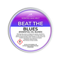 A round tub of Scents & Scentsibility 'Beat the Blues' scented wax melt, featuring a purple-to-white gradient label with product details and a hazard symbol.