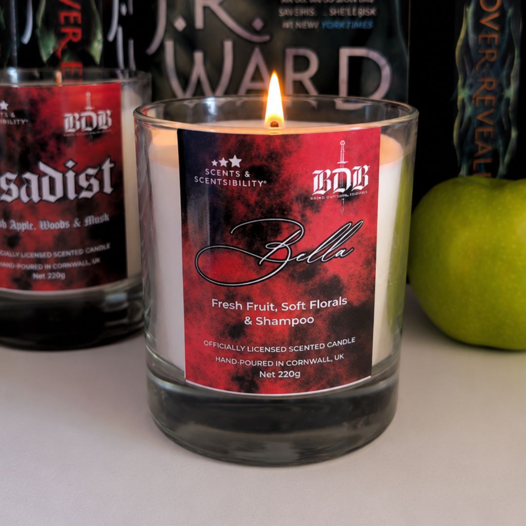 Candle labeled 'Bella' with a visible flame, surrounded by other candles and a green apple.