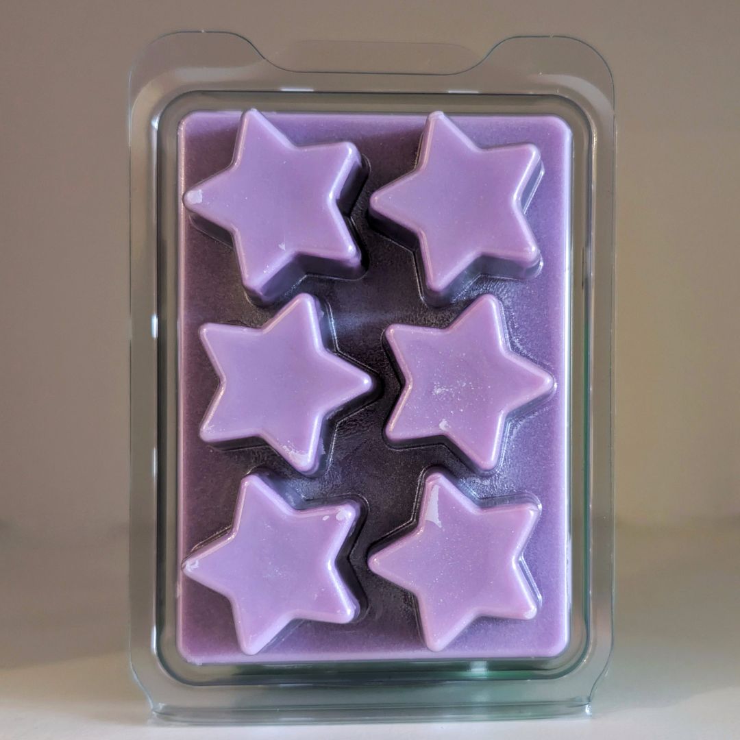 Purple star-shaped wax melts in a clear plastic mold on a beige background