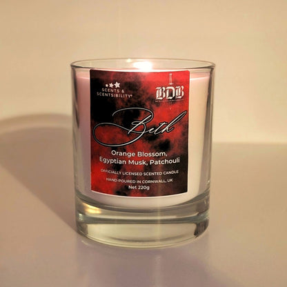 Scented candle with a red label sayinf 'Beth' on a neutral background