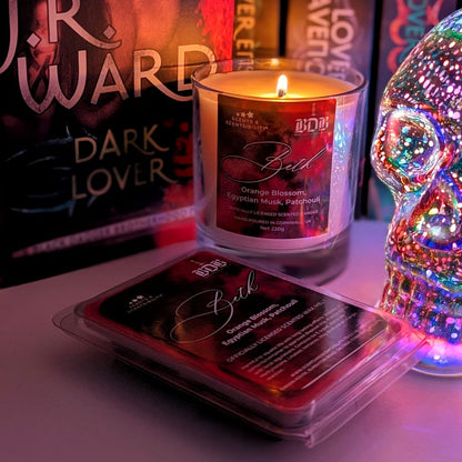 Candle and wax melt with packaging and a colorful skull decoration on a surface.