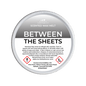 Scented wax melt container labeled 'Between the Sheets' with warning information on a green background