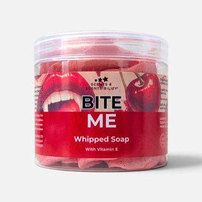 A clear plastic jar of Scents & Scentsibility 'Bite Me' Whipped Soap, showing the dark pink soap inside, with a red and white label featuring a cherry and lips graphic.