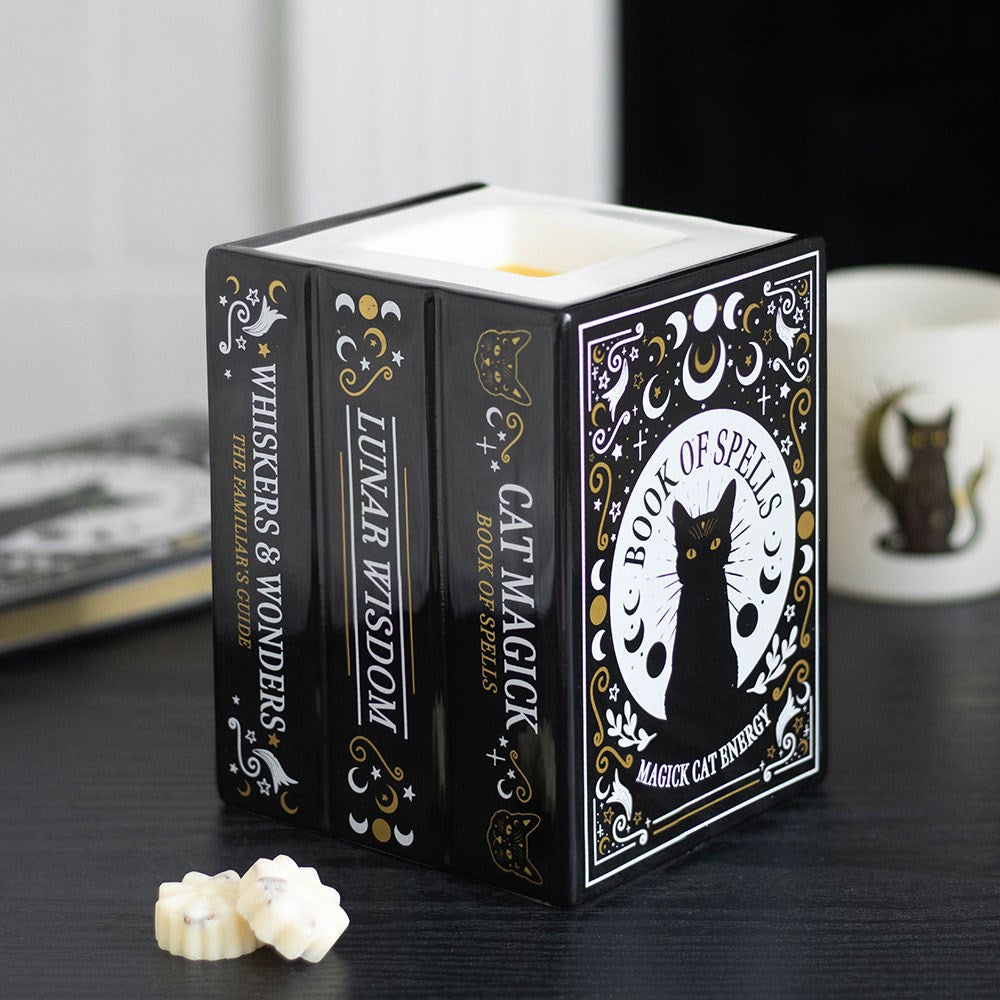 Decorative wax melt and oil burner with book design featuring a black cat on a dark surface.