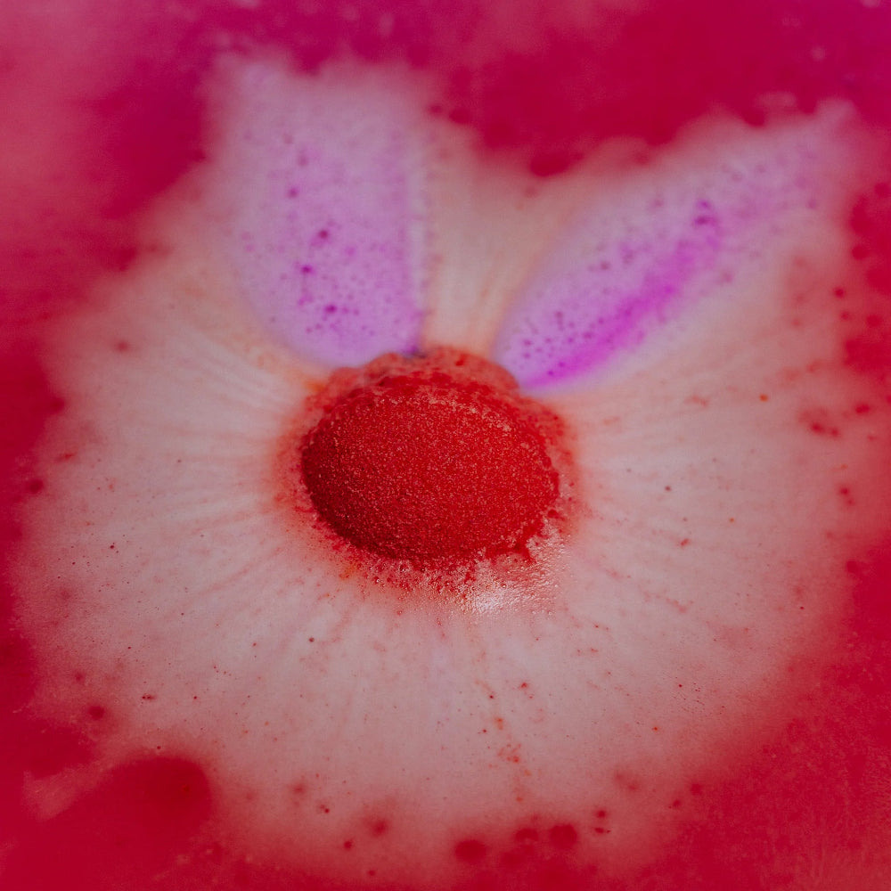 A foaming bath bomb with red and purple streaks