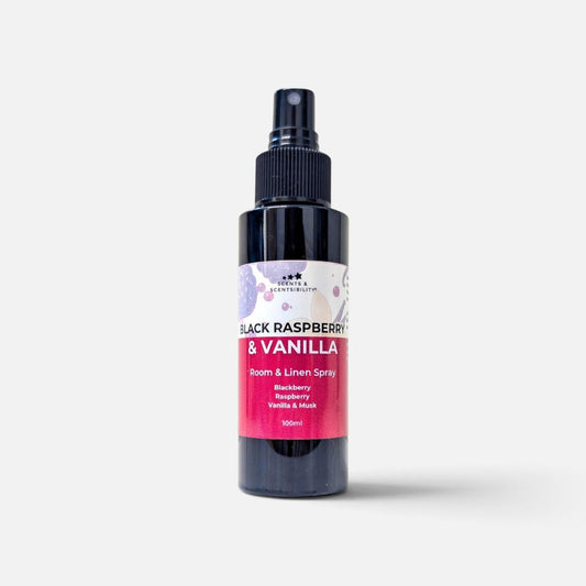 A 100ml room and linen spray bottle with a black pump and a white and pink label, featuring the scent 'Black Raspberry & Vanilla' by Scents & Scentsibility, on a light gray background.