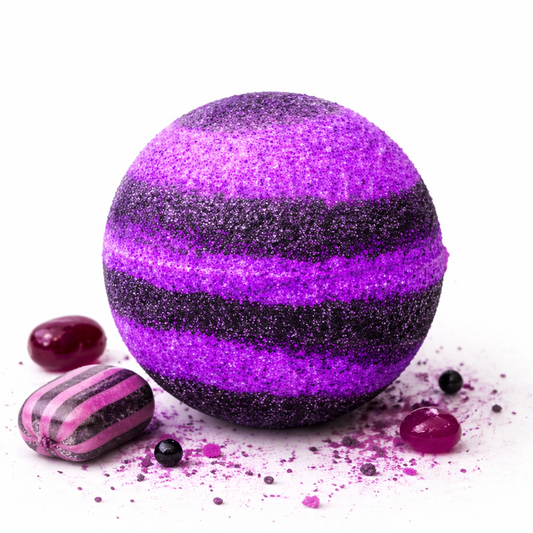A black and purple bath bomb surrounded by purple sweets