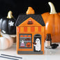 Halloween-themed candy house wax melt and oil burner with pumpkins and ghost decorations on a table.