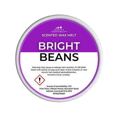 A Scents & Scentuality 'Bright Beans' scented wax melt, featuring a purple and white label with product details and a warning symbol, set against a solid dark green background.