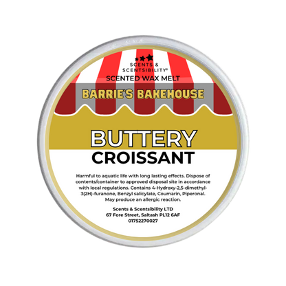 A round metal tub of Scents & Scentsibility 'Buttery Croissant' scented wax melt by Barrie's Bakehouse, featuring a label with red and white striped bakery awnings and yellow and white text.