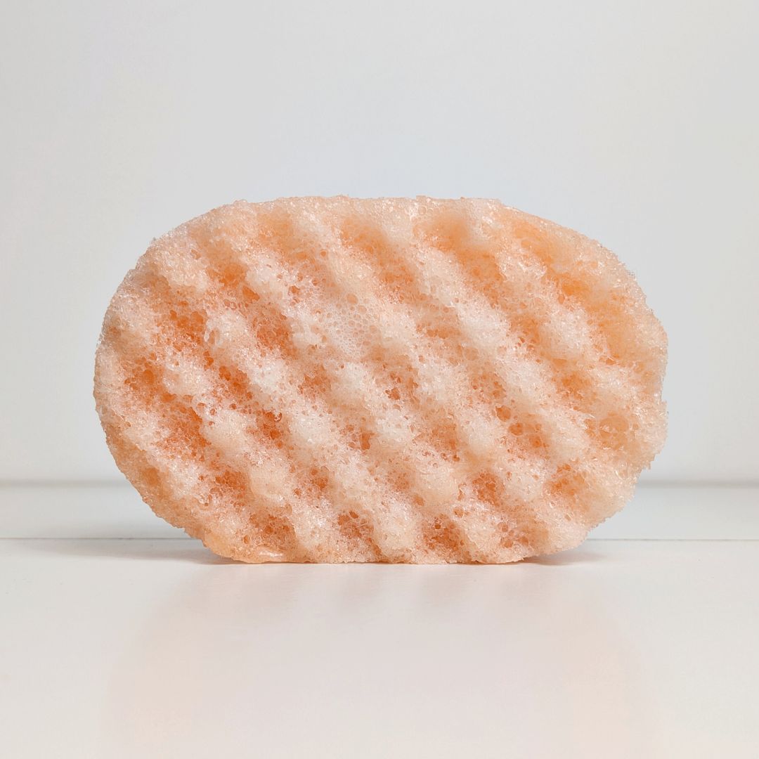 A gold-coloured sponge with exfoliating surface, loaded with soap.