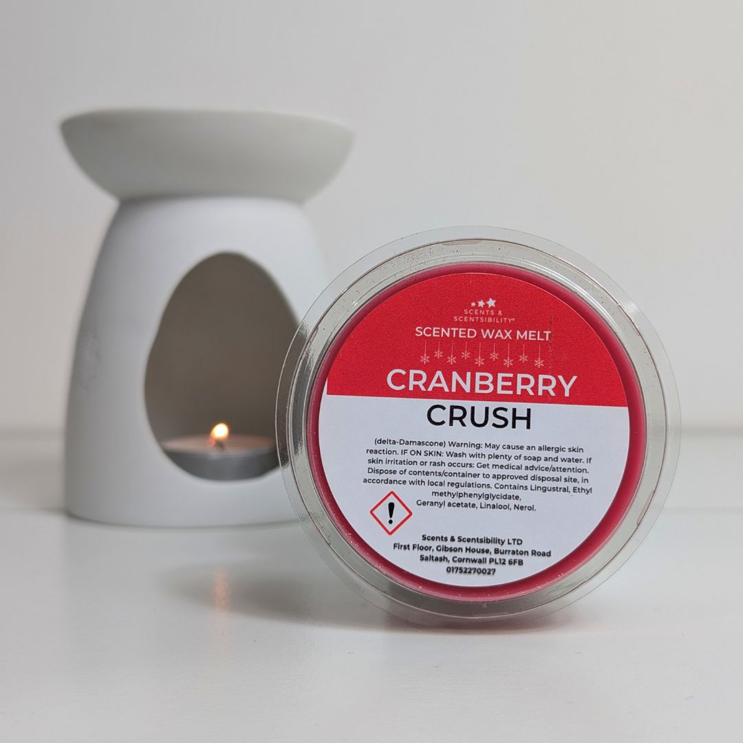 Scented wax melt container labeled 'Cranberry Crush' with a white wax warmer in the background.