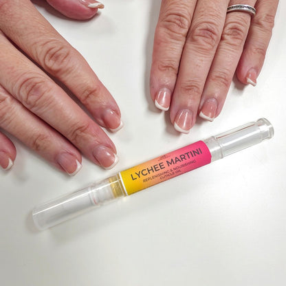 Cuticle Pen labeled 'Lychee Martini' with hands holding a white object in the background