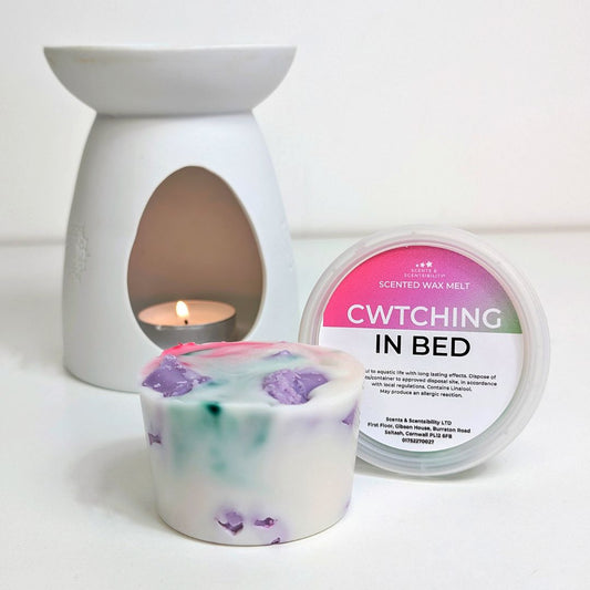 Scented wax melt container with a lit wax melt burner and packaging on a white background