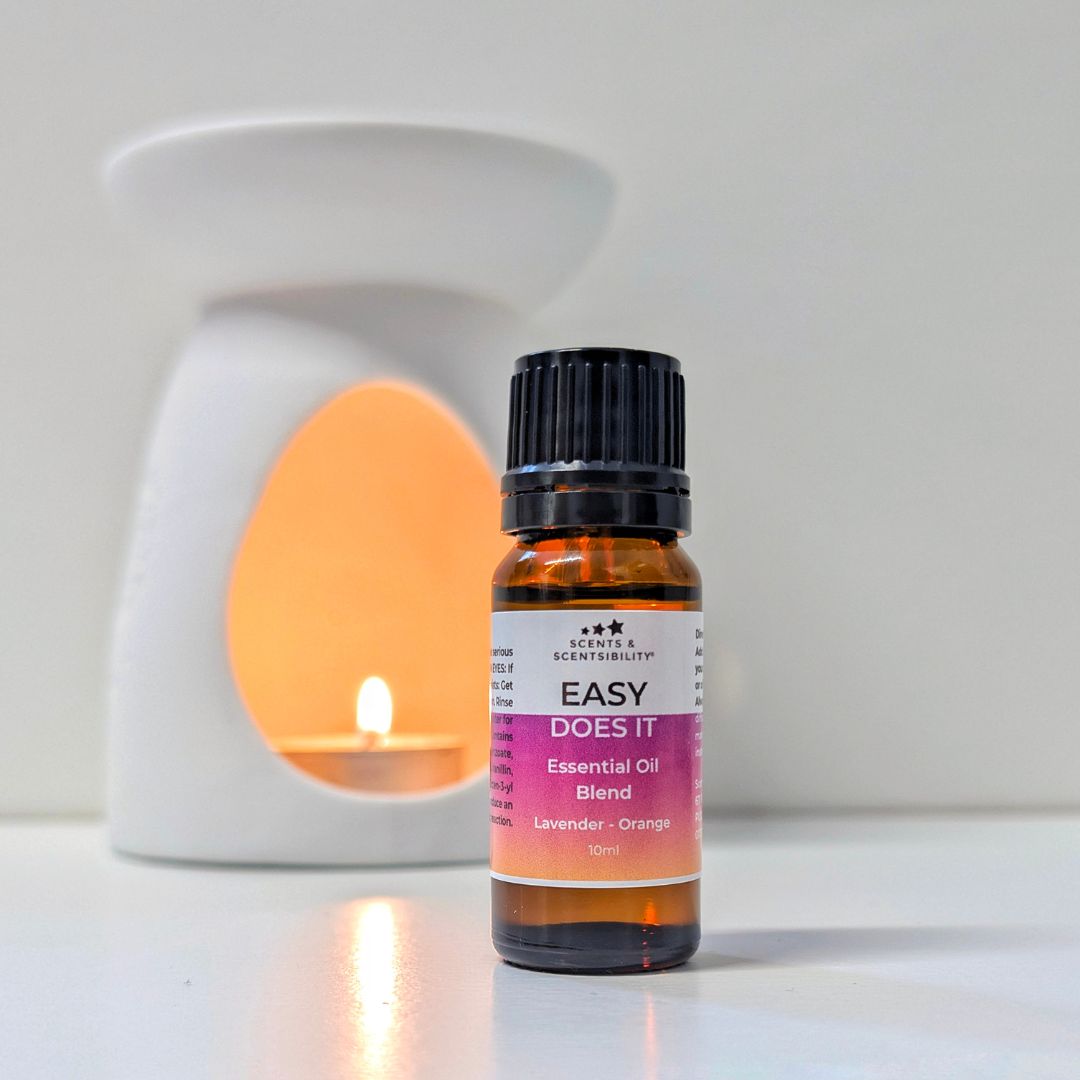 An amber bottle of essential oil with a black cap in front of a white oil burner
