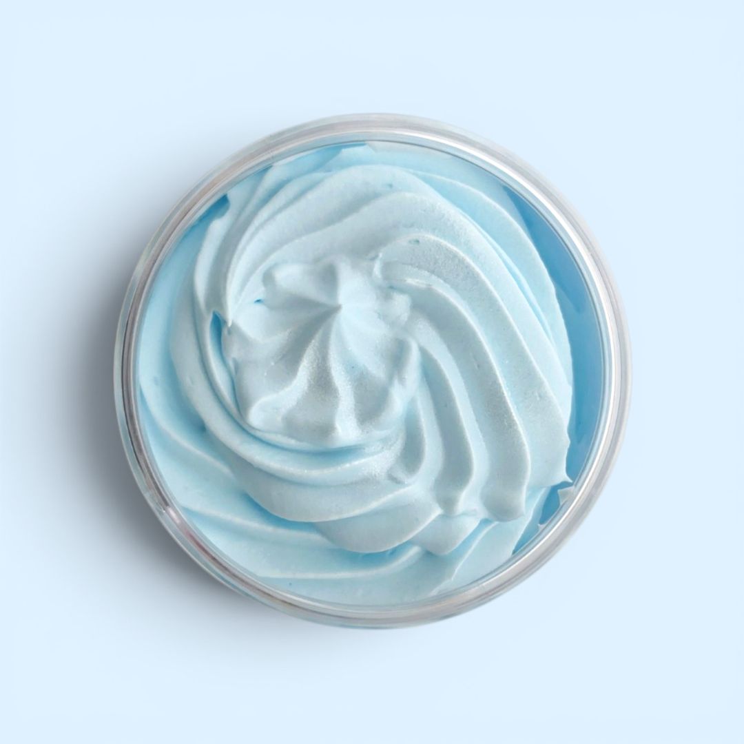 Close-up of a swirl of blue and white whipped soap in a container on a light blue background