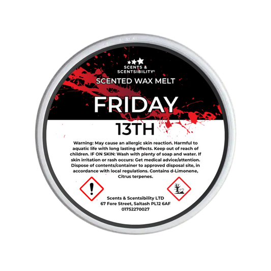 A round tin of Scents & Scentsibility Friday 13th Scented Wax Melt, featuring a black and white label with red blood-splatter graphics and hazard symbols.