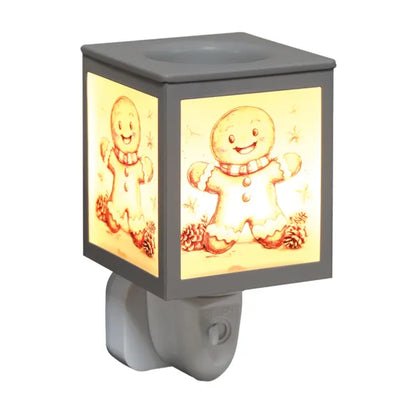 A square gingerbread-themed wax melt warmer with a white plastic plug-in base and sides, featuring a warm yellow illuminated panel with a smiling gingerbread man illustration and small star and pinecone details.