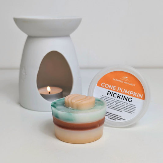 Scented wax melt with packaging labeled 'Gone Pumpkin Picking' next to a wax warmer.