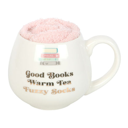 White mug with pink fuzzy interior, text 'Good Books Warm Tea Fuzzy Socks', and a small flag design.