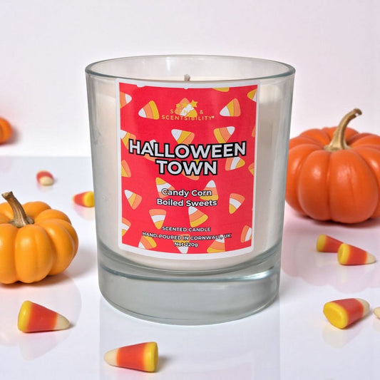 A glass candle with a red label saying 'Halloween Town' with a Candy Corn pattern on. 