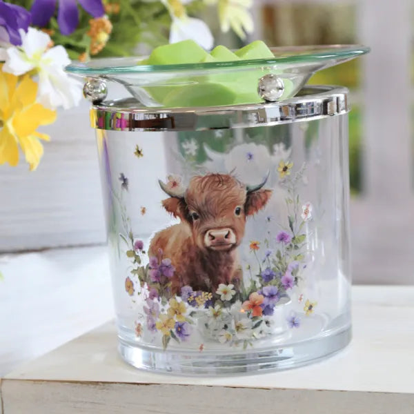 Glass wax melt and oil burner with a cow and floral design on a white surface with flowers in the background