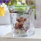 Glass wax melt and oil burner with a cow and floral design on a white surface with flowers in the background