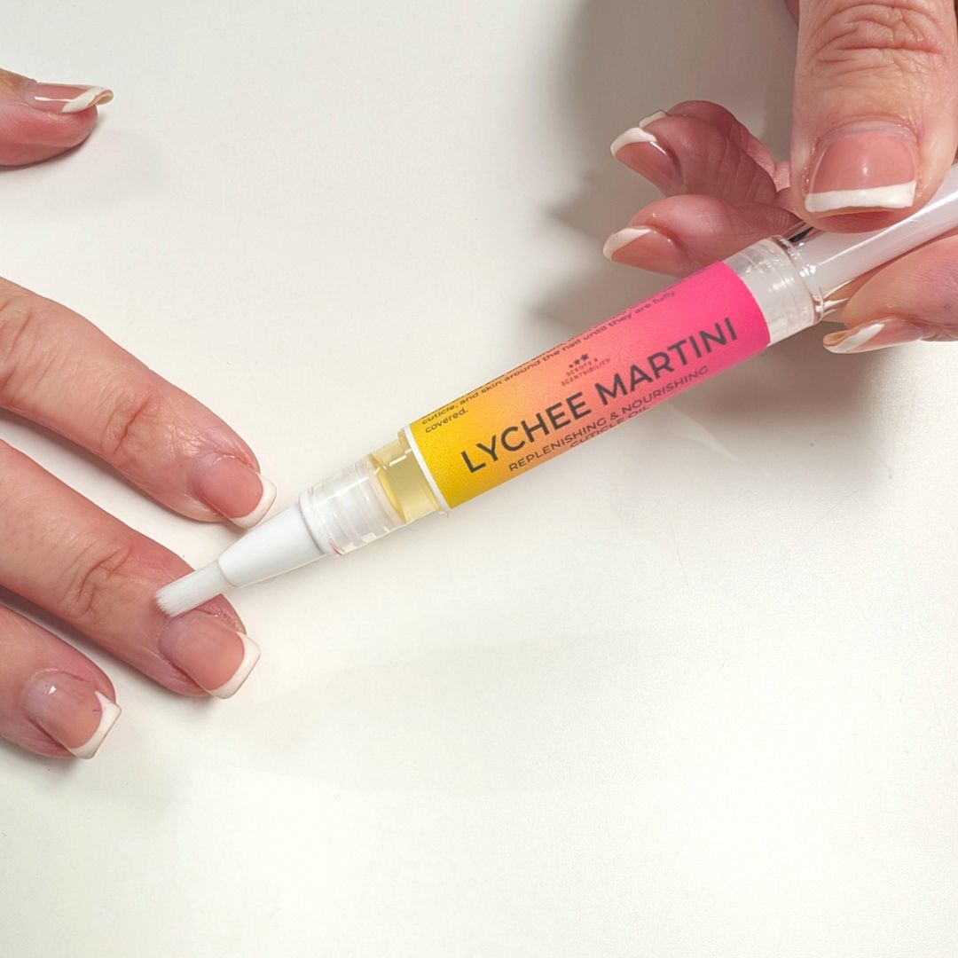 Hand holding a 'Lychee Martini' cuticle pen on a white background