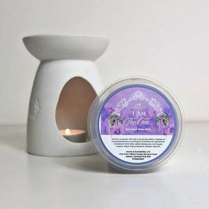 Scented wax melt container with a purple label and a white candle holder with a lit candle on a light background.