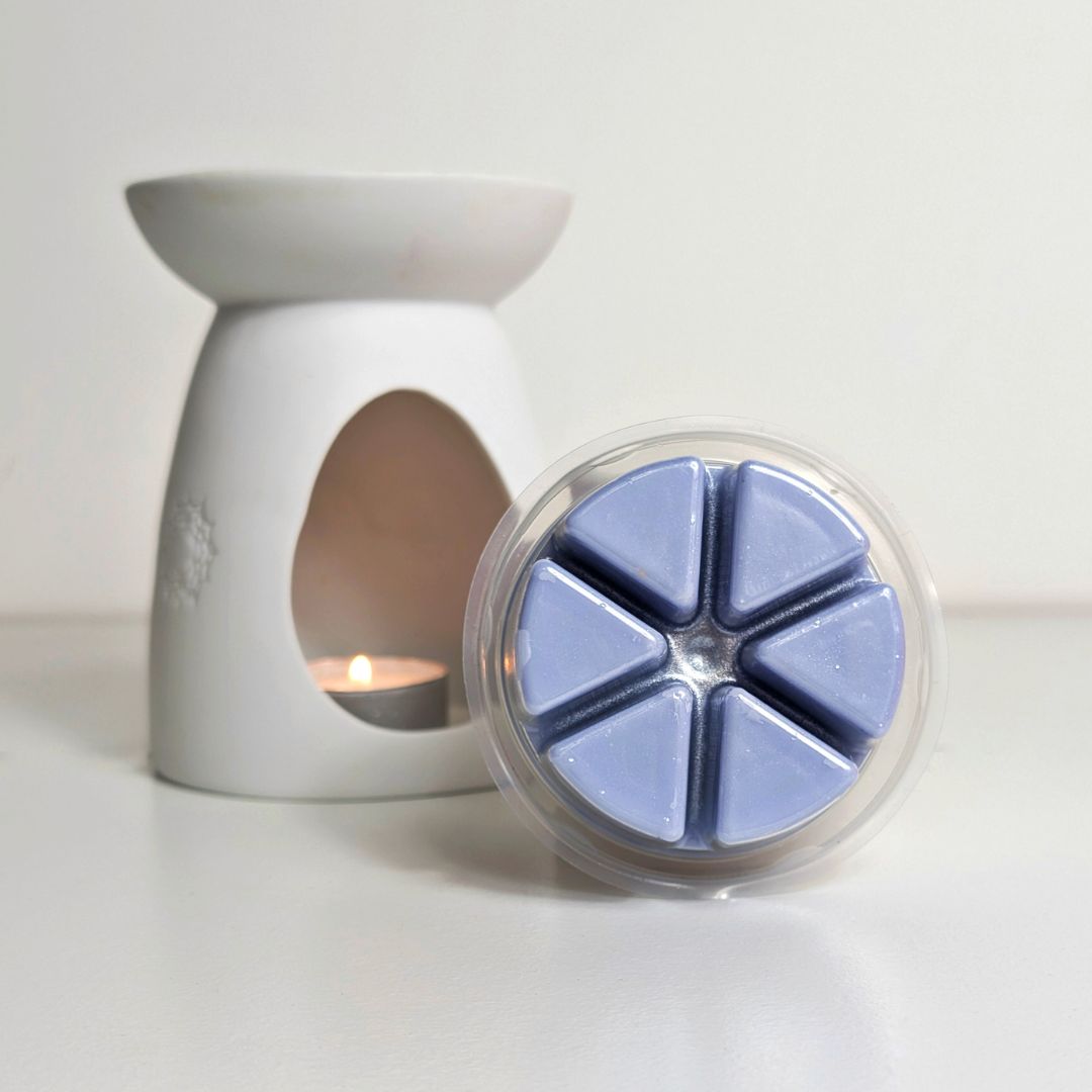 White wax warmer with a container of blue wax melts on a white background