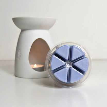 White wax warmer with a container of blue wax melts on a white background