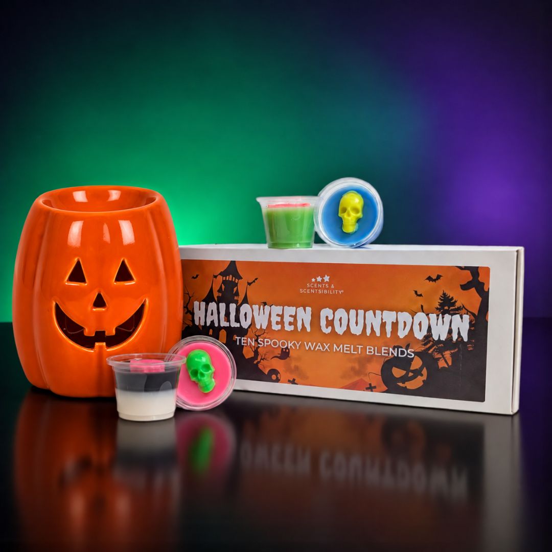 Halloween Countdown wax melt blend kit by Scents & Scentsibility featuring an orange jack-o'-lantern-shaped wax burner, a product box with spooky graphics, and small wax melt pots with colorful lids, set against a dark background with green and purple lighting.