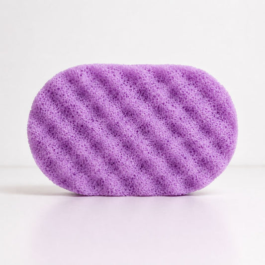 A purple oval-shaped textured sponge with soap, shown on a clean white background.