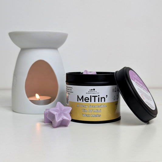 Container of Meltin' wax melts with a white wax melt and a candle in the background.