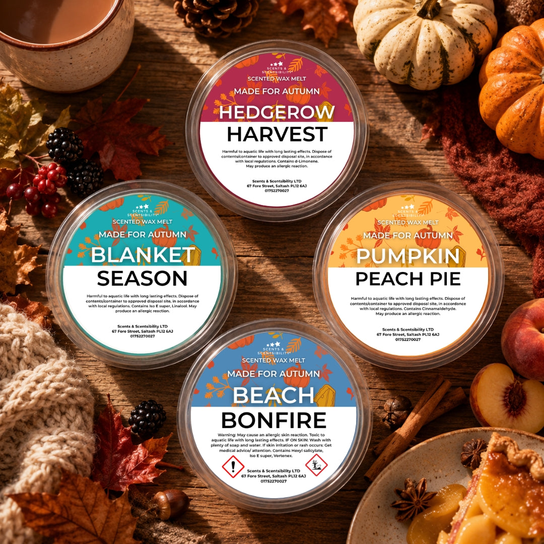 Four round scented wax melts in clear plastic tubs arranged on a rustic wooden surface with autumn-themed props including pumpkins, leaves, cinnamon, and a bowl of tea. The labels read Hedgerow Harvest, Blanket Season, Pumpkin Peach Pie, and Beach Bonfire.