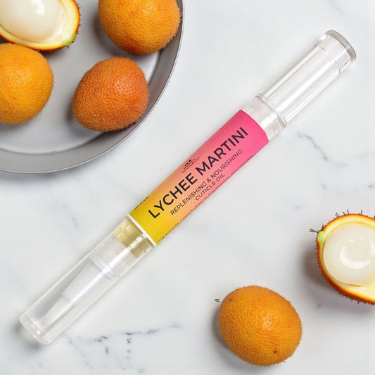 Lychee Martini cuticle pen with lychees on a marble surface