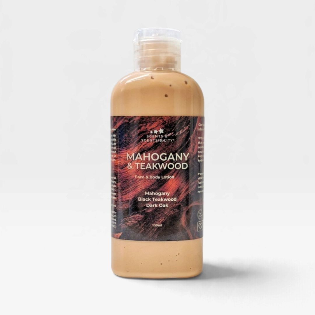 A bottle of face and body lotion from the brand Scents & Scentsibility, labeled 'Mahogany & Teakwood'. The product is filled with a light brown lotion and features a brown label, set against a clean white background.