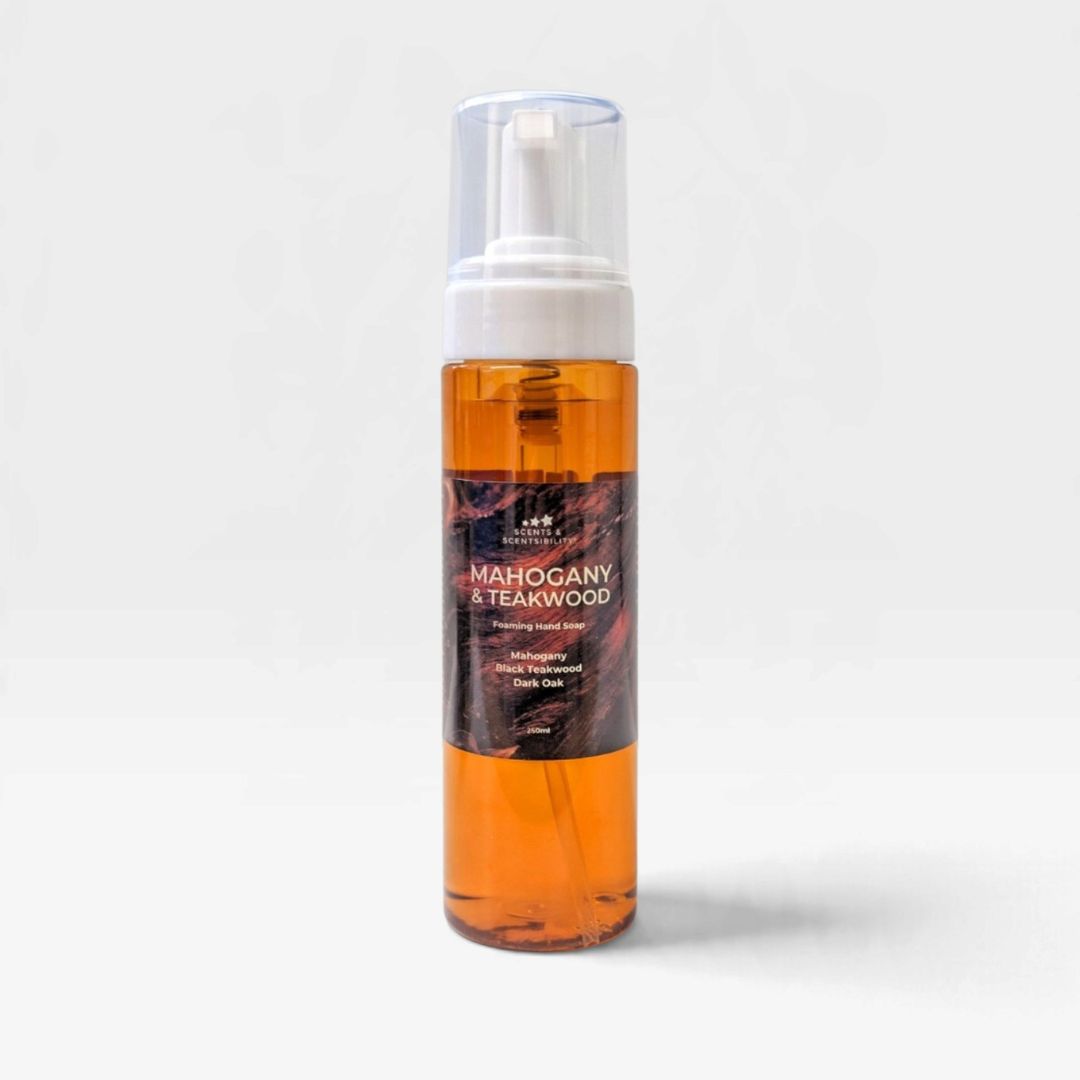 A clear plastic pump bottle filled with amber-orange liquid, featuring a white pump and a dark brown label that reads 'Mahogany & Teakwood'. The bottle is centered against a clean, light gray background with a soft shadow.