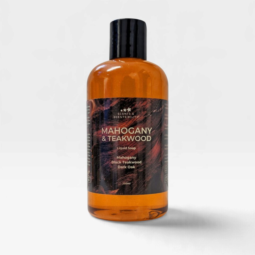 A 500ml bottle of Scents & Scentsibility liquid soap, Mahogany & Teakwood scent, featuring an amber-colored translucent bottle, a black cap, and a dark wood-grain patterned label, set against a light gray background.
