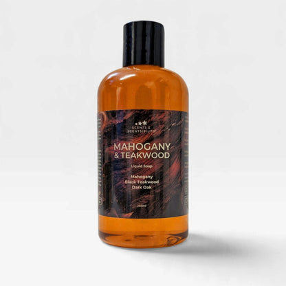 A 500ml bottle of Scents & Scentsibility liquid soap, Mahogany & Teakwood scent, featuring an amber-colored translucent bottle, a black cap, and a dark wood-grain patterned label, set against a light gray background.