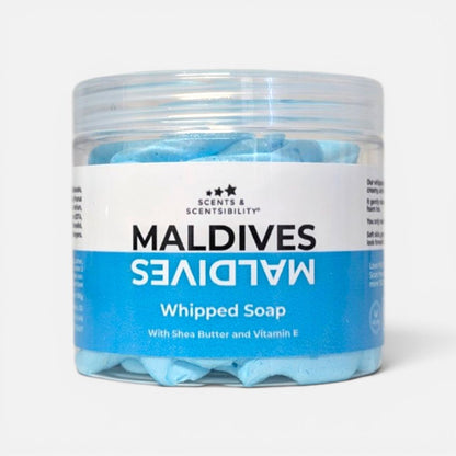 A clear plastic jar of Scents & Scentsibility Maldives Whipped Soap, showing light blue whipped soap inside, with a white and blue label on a light gray background.
